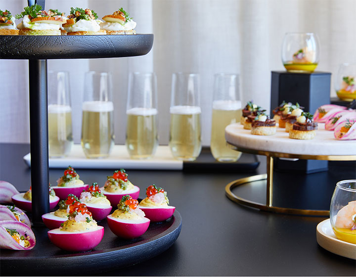 champagne glasses and other hors d’oeuvres set on a table for a catering event