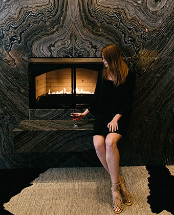 woman drinking wine in front of Lobby Fireplace