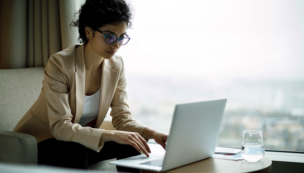 Woman working on a laptop in a hotel room