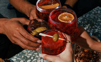 Hands cheersing cocktails at Eden Rooftop Bar