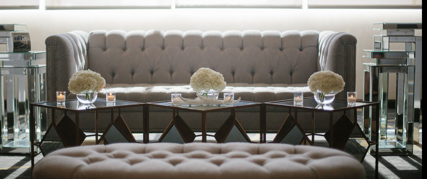 social set up with light gray couches and centerpieces on glass side tables